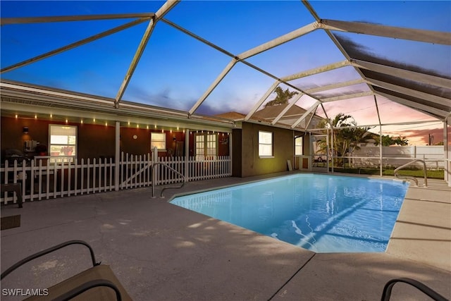 pool at dusk featuring a patio and a lanai