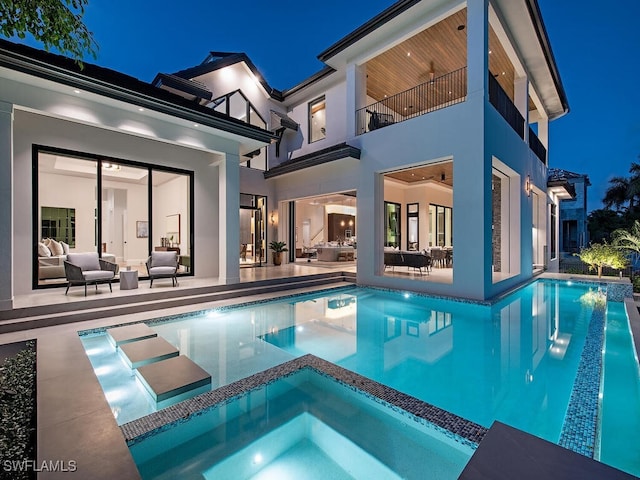 pool at twilight with an in ground hot tub, an outdoor living space, and a patio area