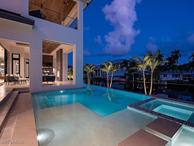 pool at dusk featuring a patio area and an in ground hot tub