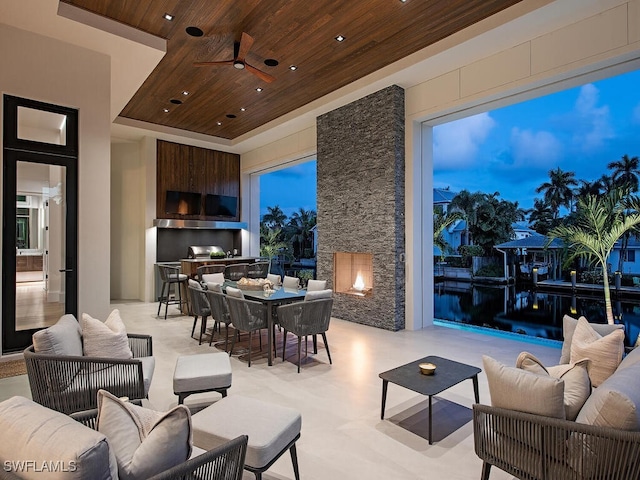 living room featuring ceiling fan, a high ceiling, wooden ceiling, and an outdoor stone fireplace