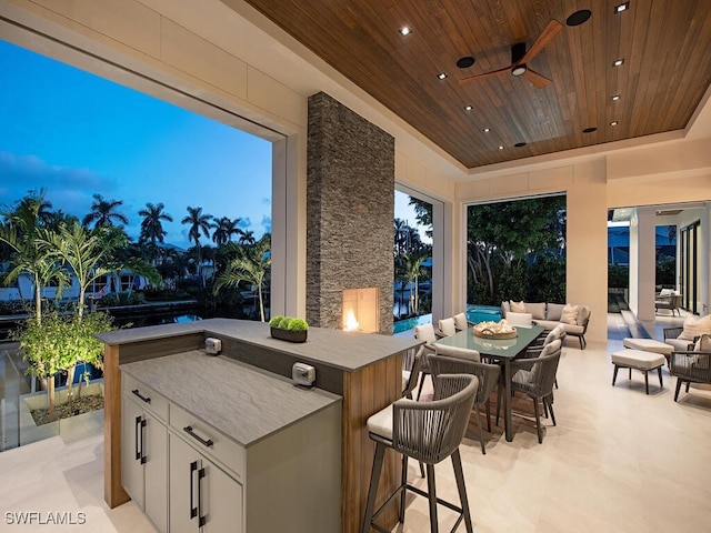 patio terrace at dusk featuring ceiling fan, an outdoor living space, and exterior kitchen