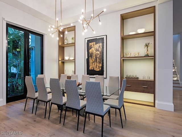 dining area with light hardwood / wood-style flooring, built in features, and a notable chandelier