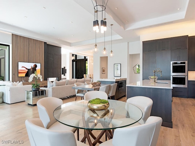 dining area with light hardwood / wood-style flooring, sink, and a chandelier