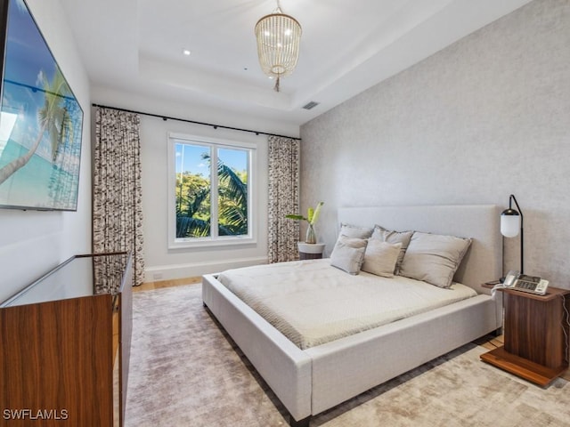 bedroom with a notable chandelier and a tray ceiling