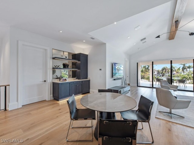 dining area featuring lofted ceiling with beams and light hardwood / wood-style floors