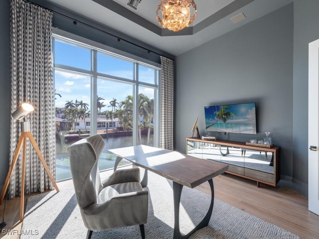 home office featuring hardwood / wood-style floors, a notable chandelier, and a raised ceiling