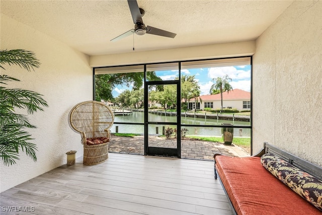 sunroom / solarium featuring a water view and ceiling fan