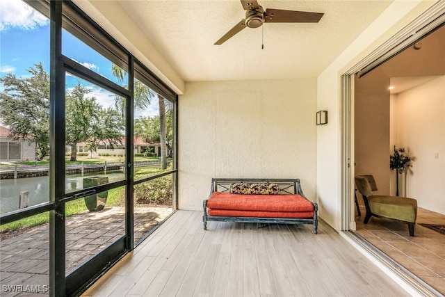 sunroom / solarium with a water view and ceiling fan