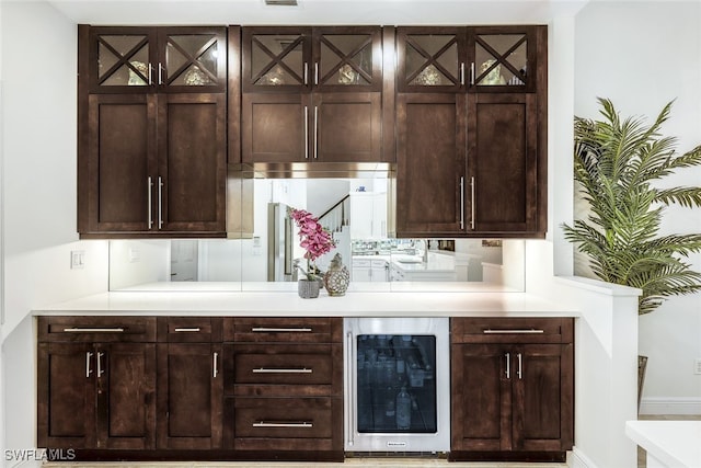 bar with dark brown cabinetry and beverage cooler