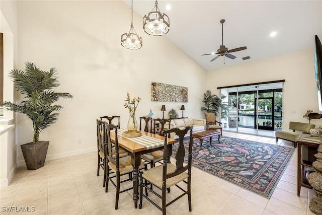 dining space featuring ceiling fan with notable chandelier, light tile patterned floors, and high vaulted ceiling