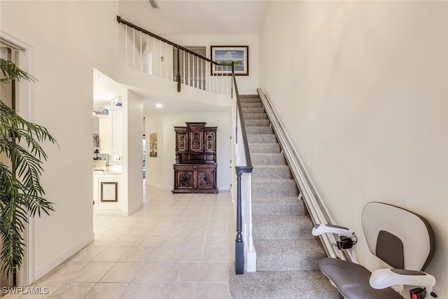 stairway with tile patterned flooring and a high ceiling