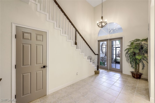 tiled entrance foyer featuring a chandelier, french doors, and a towering ceiling