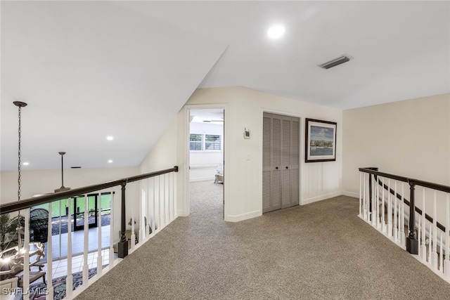 hall featuring carpet flooring and vaulted ceiling