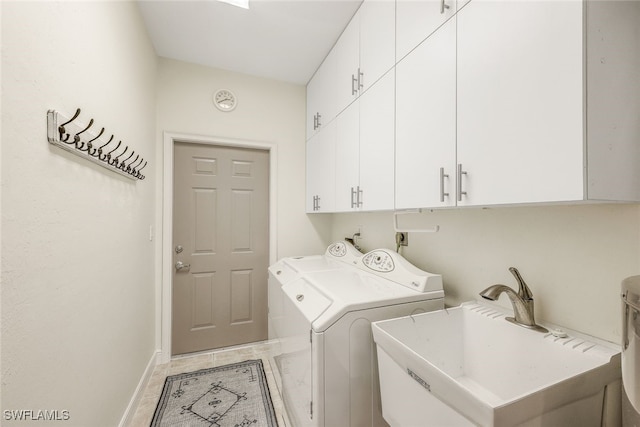 clothes washing area featuring washer and clothes dryer, sink, light tile patterned floors, and cabinets