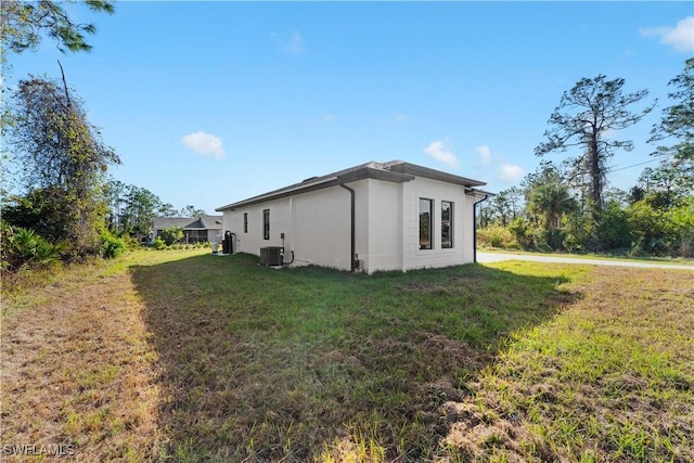 view of side of home with cooling unit and a yard