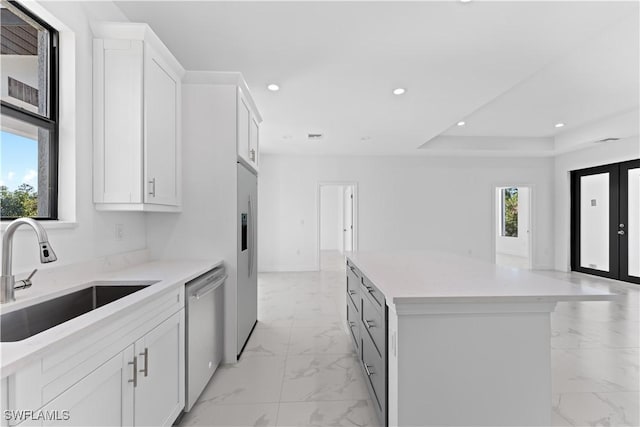 kitchen featuring plenty of natural light, sink, stainless steel dishwasher, and white cabinets