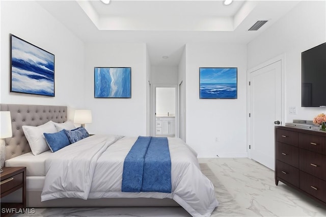 bedroom with connected bathroom and a tray ceiling