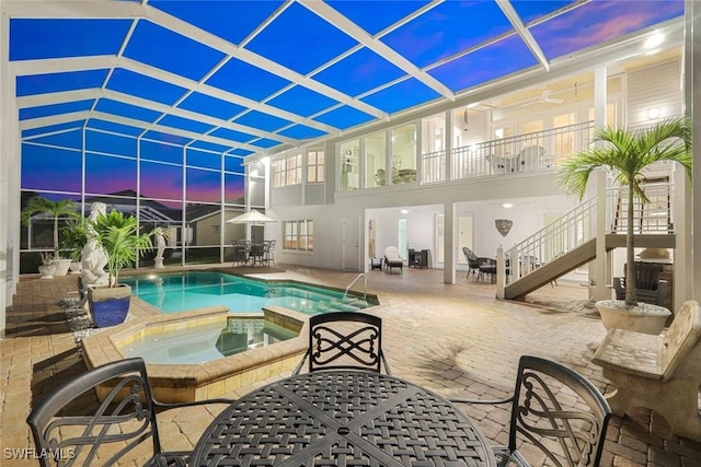 pool at dusk featuring an in ground hot tub and a patio area