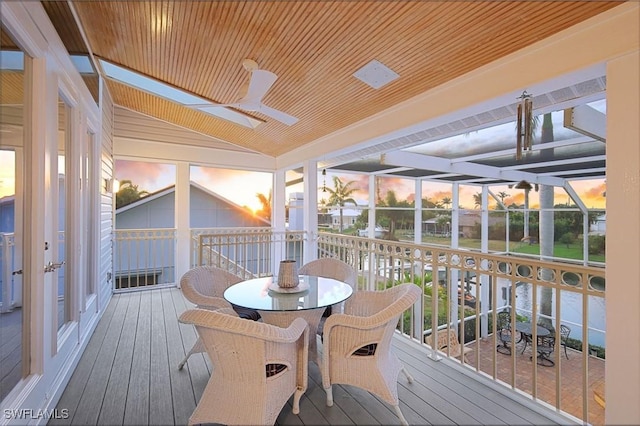 sunroom / solarium with lofted ceiling, wooden ceiling, ceiling fan, and a water view