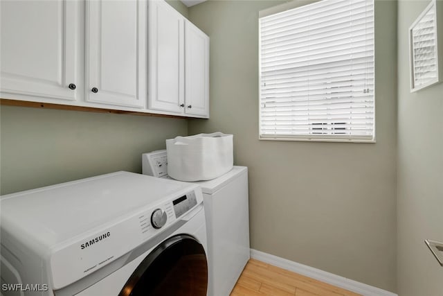 laundry area with washing machine and dryer, cabinets, and light wood-type flooring