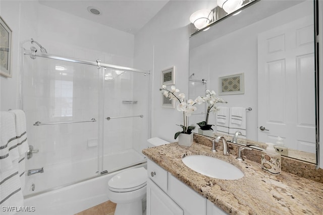 full bathroom with tile patterned floors, vanity, toilet, and bath / shower combo with glass door