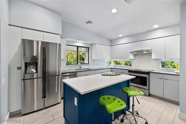 kitchen featuring a kitchen breakfast bar, a center island, white cabinets, and appliances with stainless steel finishes