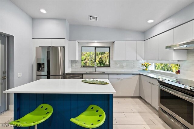 kitchen with a breakfast bar, a center island, white cabinets, sink, and appliances with stainless steel finishes