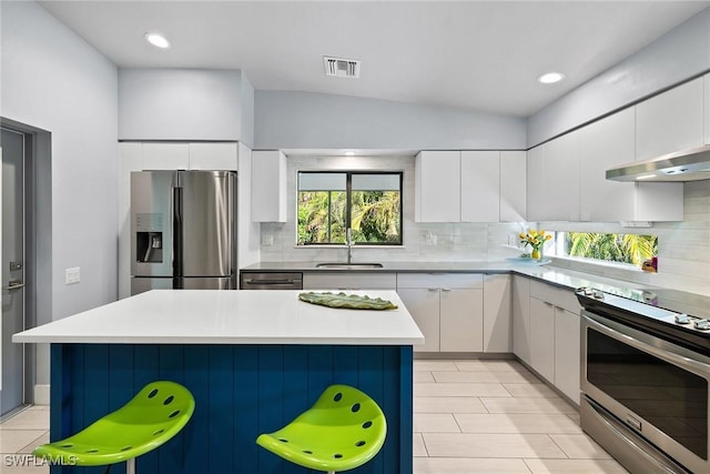 kitchen featuring sink, white cabinetry, a kitchen island, stainless steel appliances, and a kitchen bar