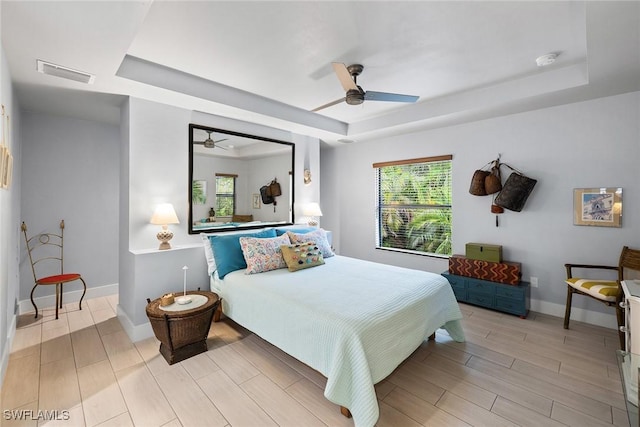 bedroom with ceiling fan and a tray ceiling