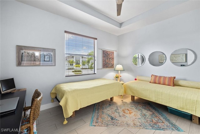 bedroom featuring a raised ceiling, ceiling fan, and light hardwood / wood-style flooring