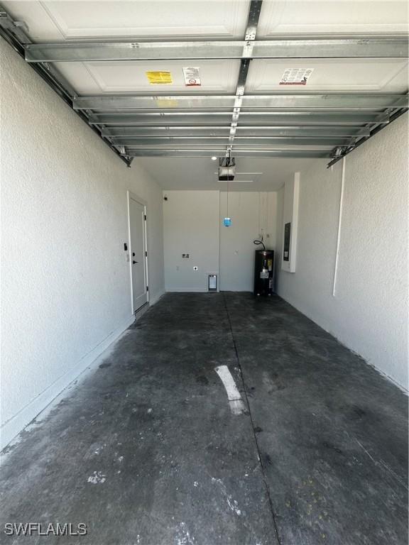 garage featuring electric water heater, electric panel, and a garage door opener