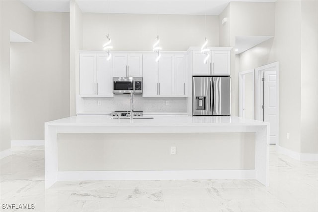 kitchen featuring white cabinets, appliances with stainless steel finishes, tasteful backsplash, and an island with sink