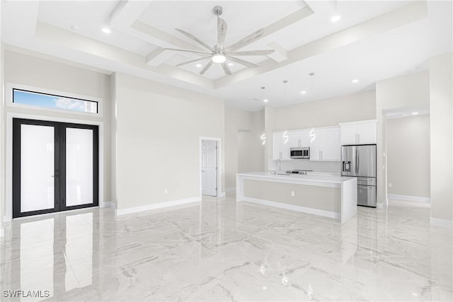 living room featuring french doors, a raised ceiling, sink, ceiling fan, and a towering ceiling