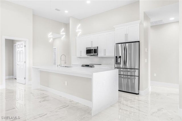 kitchen with white cabinetry, sink, a towering ceiling, a kitchen island with sink, and appliances with stainless steel finishes