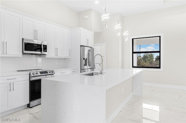 kitchen with appliances with stainless steel finishes, sink, decorative light fixtures, a center island with sink, and white cabinetry