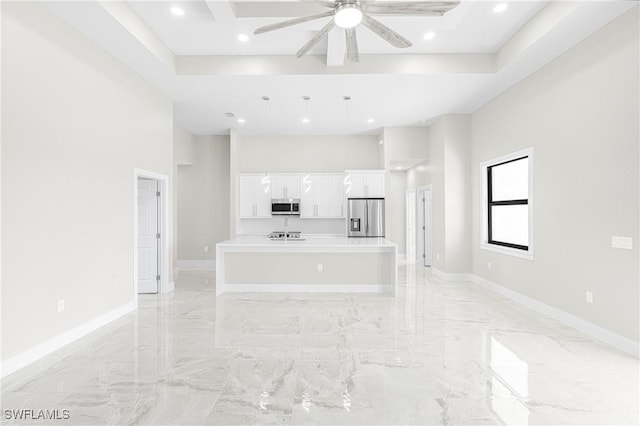 unfurnished living room featuring a raised ceiling, ceiling fan, and a towering ceiling