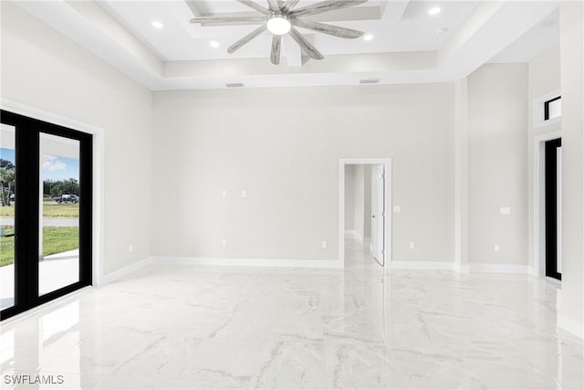 unfurnished room featuring a tray ceiling, ceiling fan, french doors, and a towering ceiling