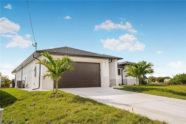 view of front of home with a front lawn, a garage, and central AC