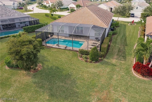 view of swimming pool featuring glass enclosure, a patio area, and a yard