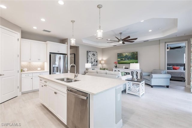 kitchen featuring a raised ceiling, sink, white cabinets, and stainless steel appliances