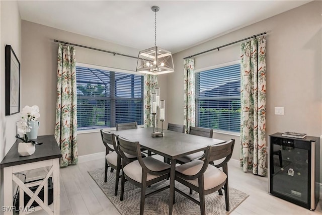 dining room with beverage cooler, a notable chandelier, and light wood-type flooring