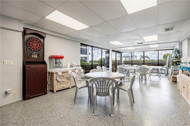 dining space featuring a wealth of natural light, visible vents, light speckled floor, and a drop ceiling