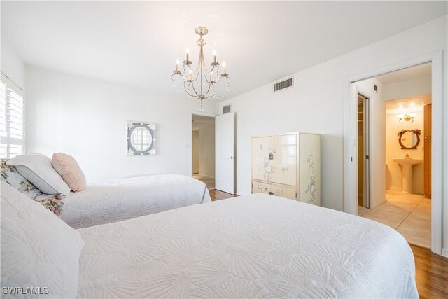 bedroom with a chandelier, visible vents, and wood finished floors