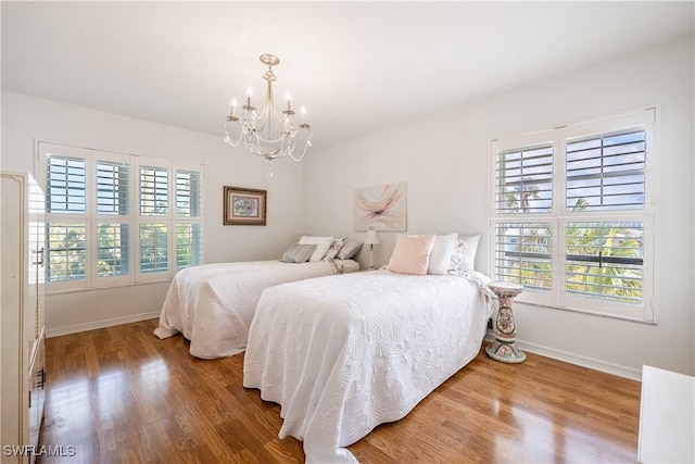 bedroom with a chandelier, wood finished floors, and baseboards