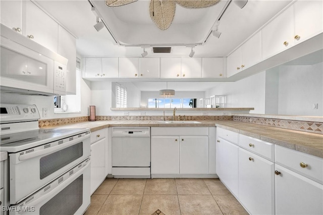 kitchen featuring light countertops, white appliances, a sink, and white cabinets