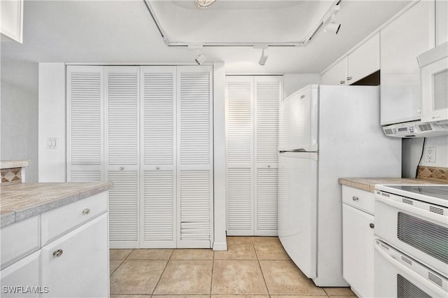 kitchen featuring light countertops, white appliances, light tile patterned flooring, and white cabinets