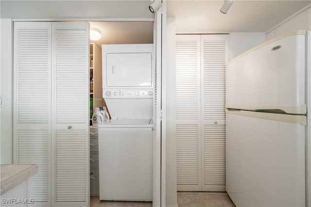 washroom with stacked washer and dryer, laundry area, and light tile patterned floors