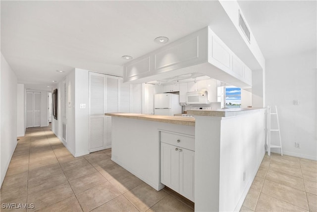 kitchen with a peninsula, white appliances, visible vents, white cabinets, and light countertops