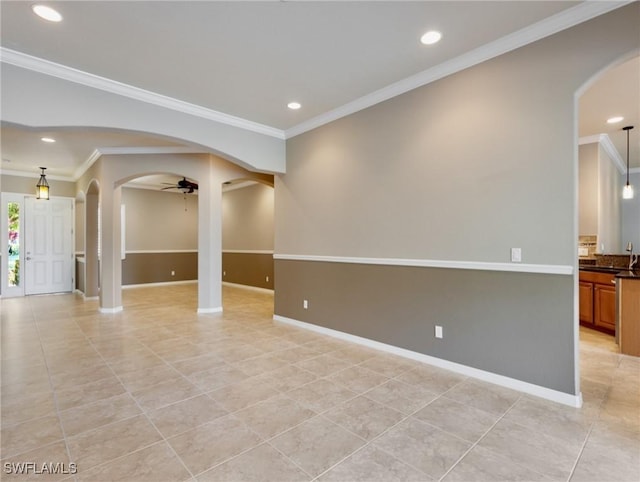 tiled empty room featuring ceiling fan, crown molding, and sink