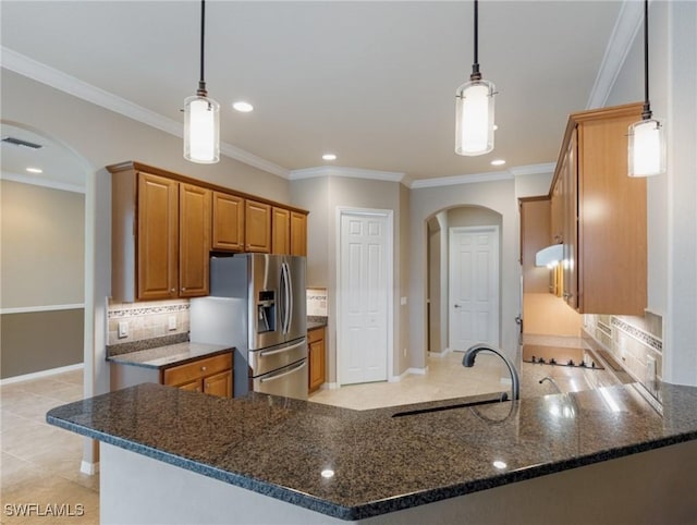 kitchen with stainless steel refrigerator with ice dispenser, pendant lighting, kitchen peninsula, and sink